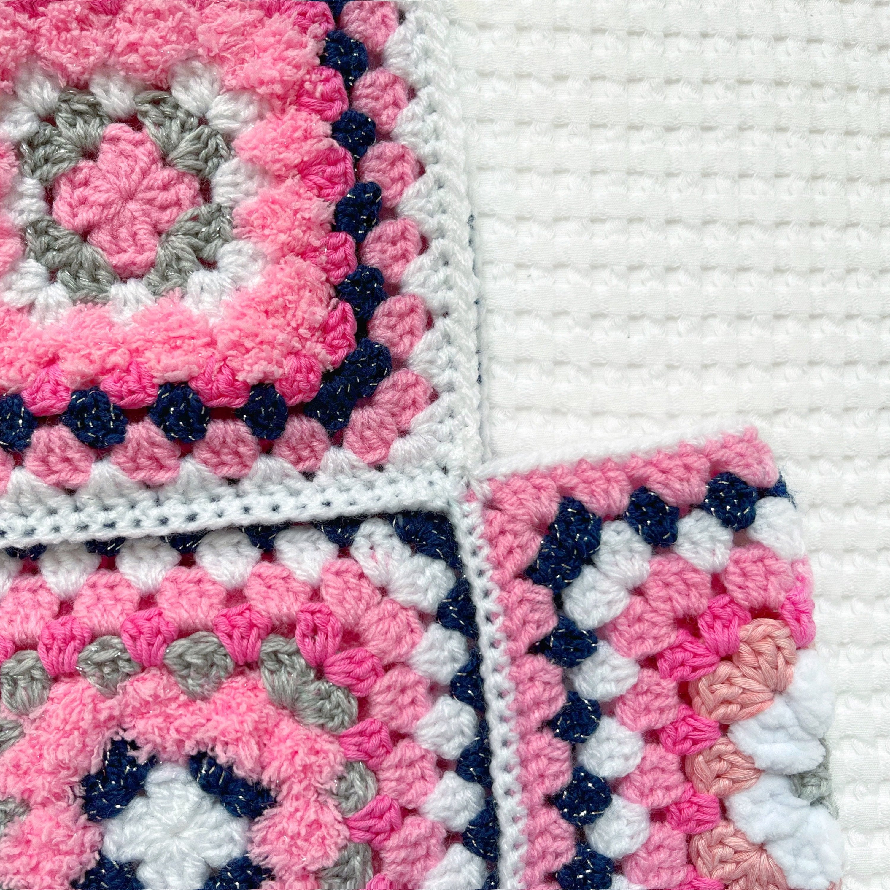 Close-up of a pink, blue, and gray crocheted balaclava with a geometric pattern.