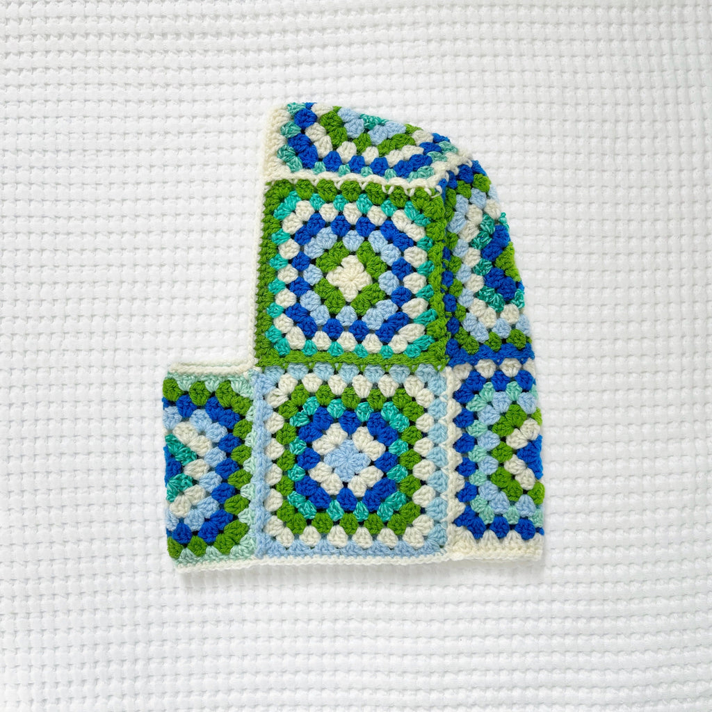 Crocheted granny square balaclava on a textured white background