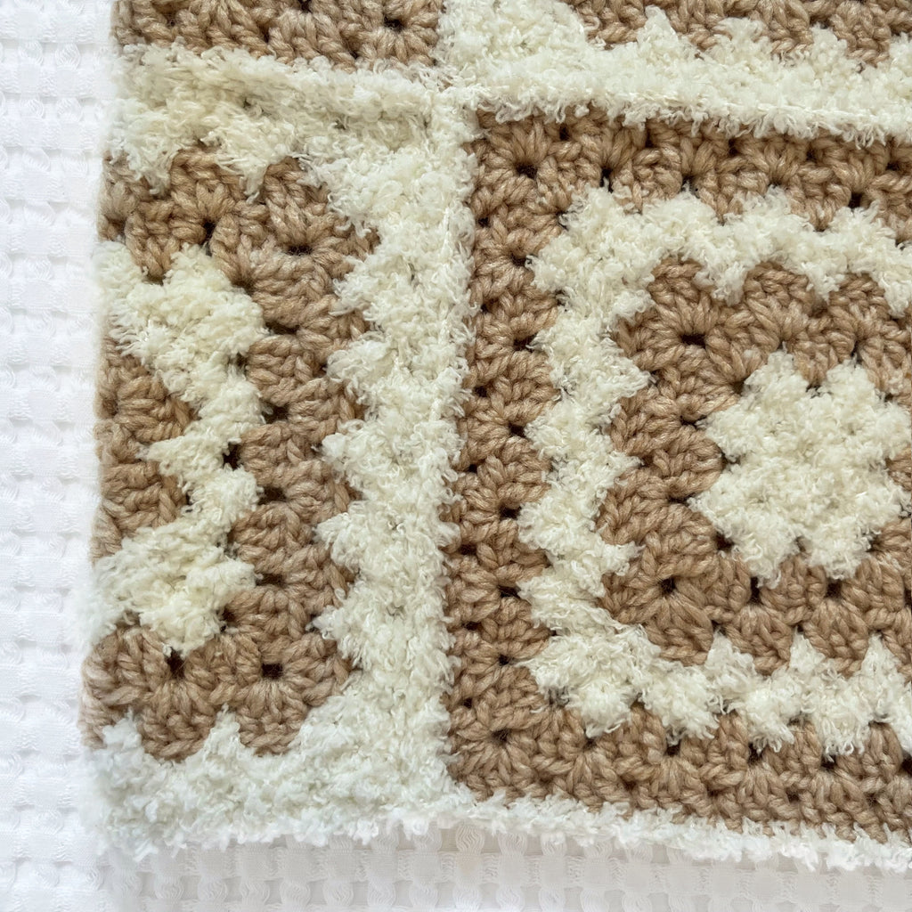 Crocheted balaclava in beige and white colors on a textured white background