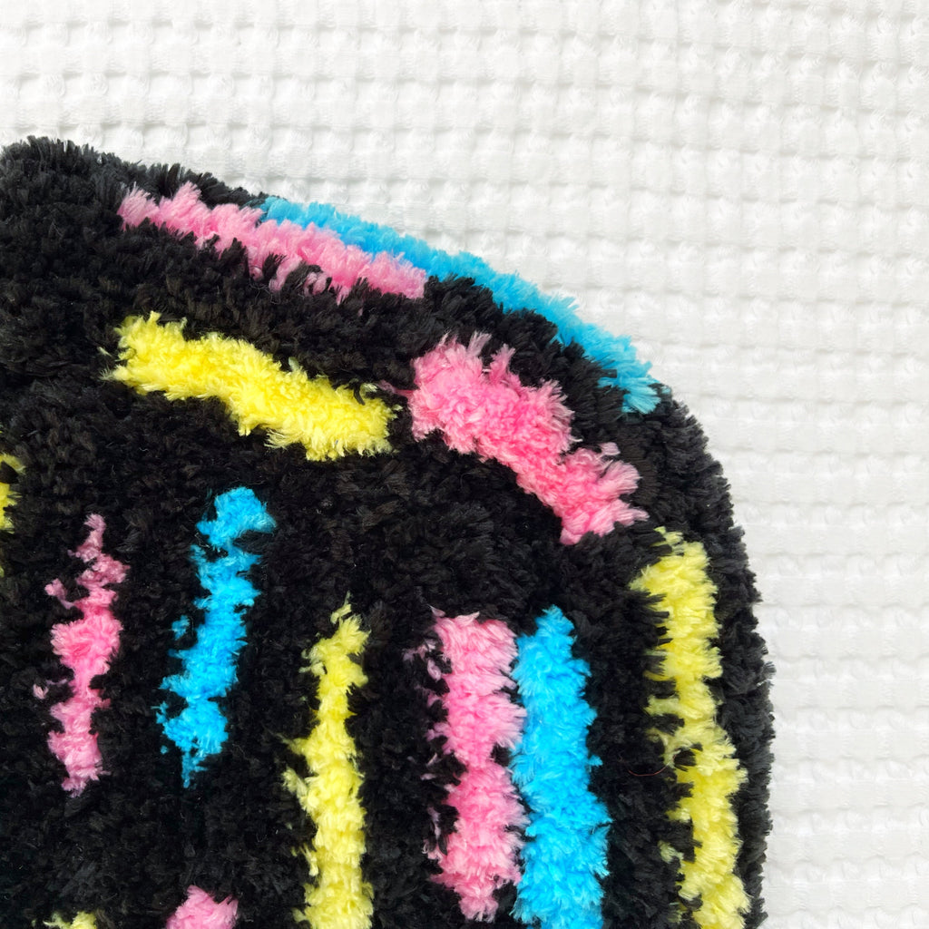 Colorful fuzzy crochet bonnet on a white textured background