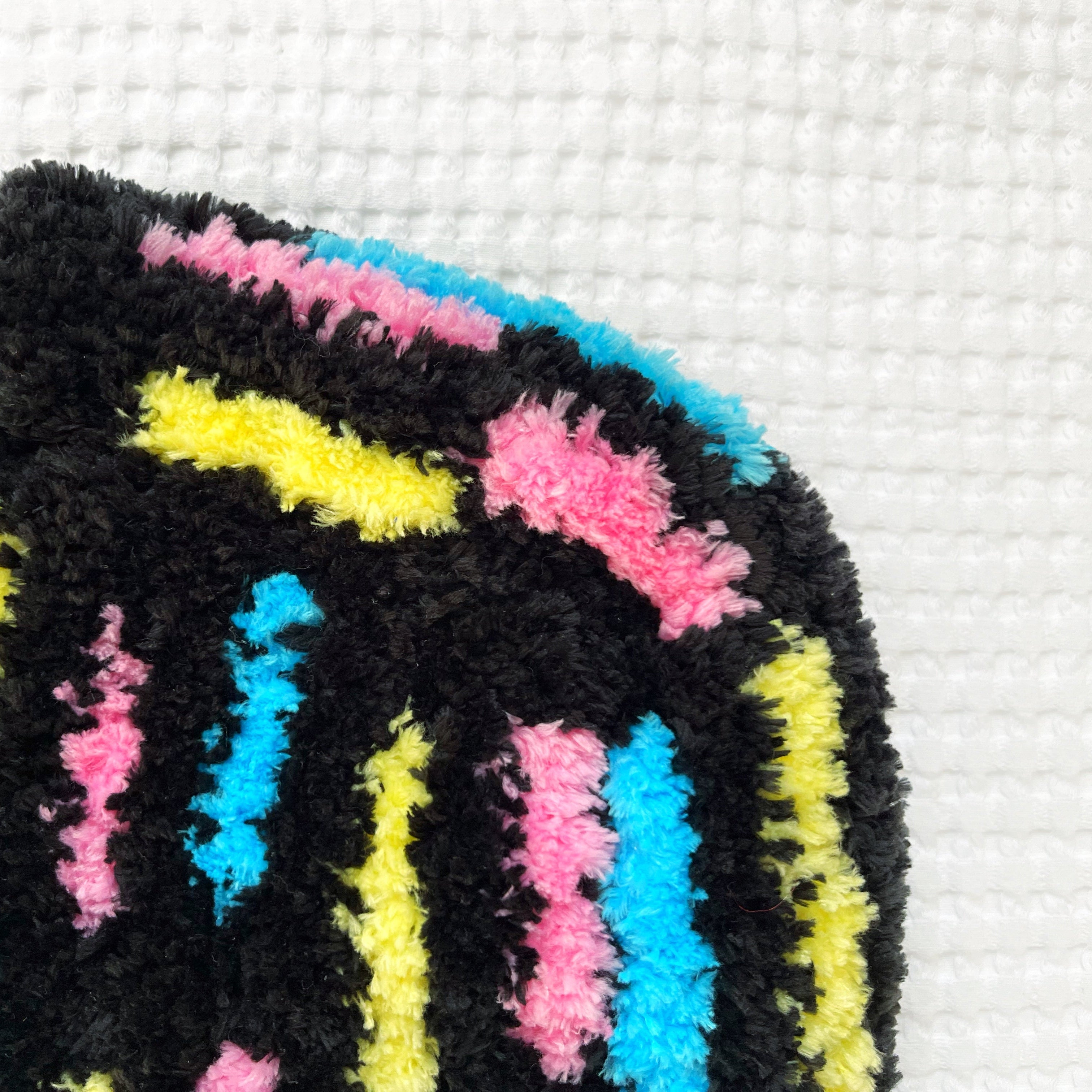 Colorful fuzzy crochet bonnet on a white textured background