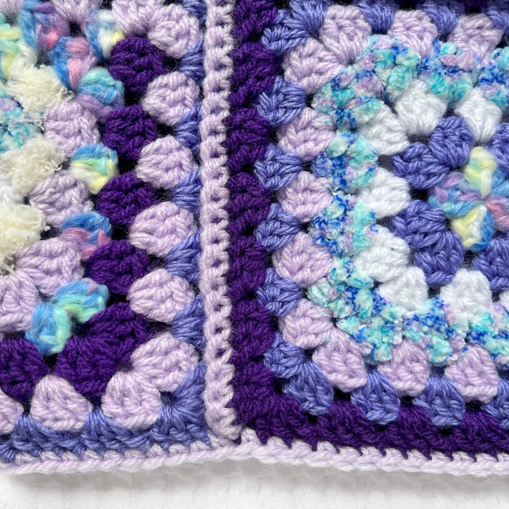Close-up of a crocheted balaclava with a purple and white border.