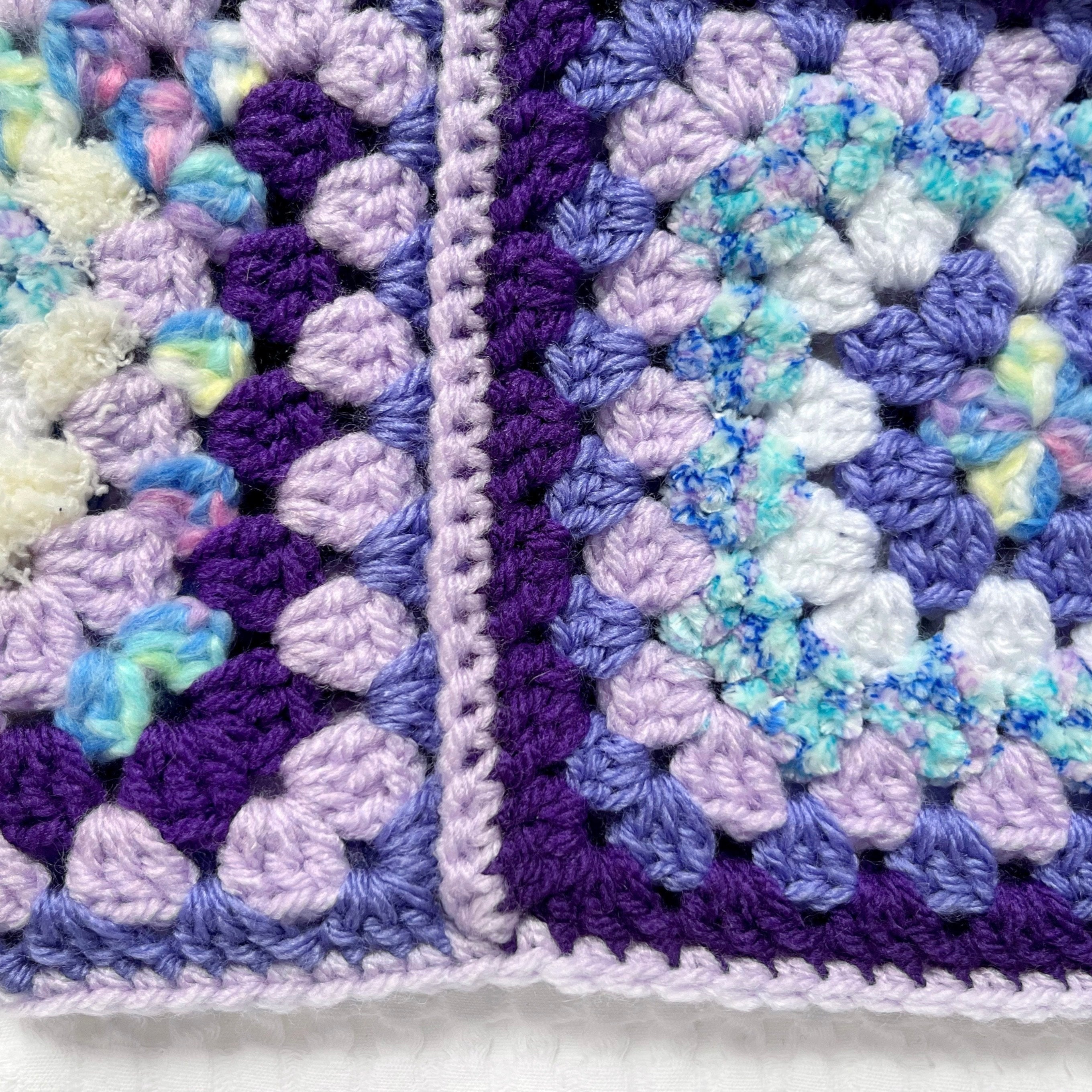 Close-up of a crocheted balaclava with a purple and white border.