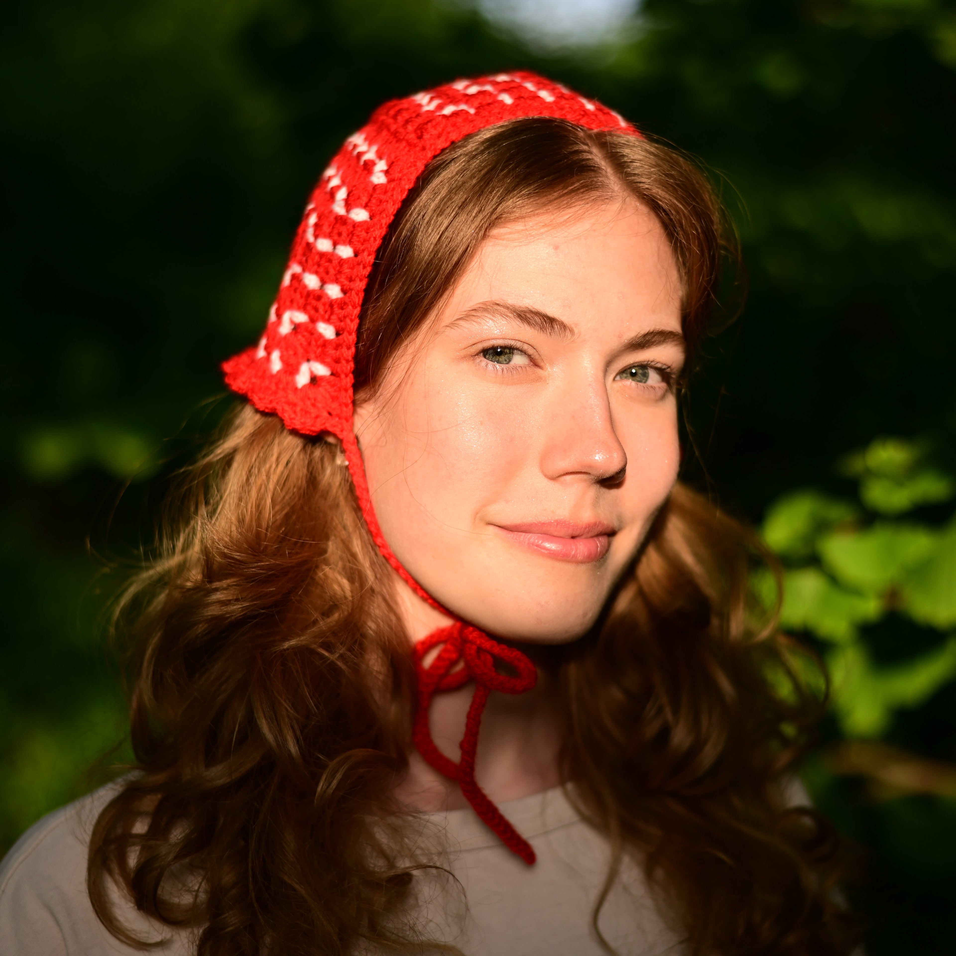 Woman wearing a red crochet bonnet with white patterns outdoors