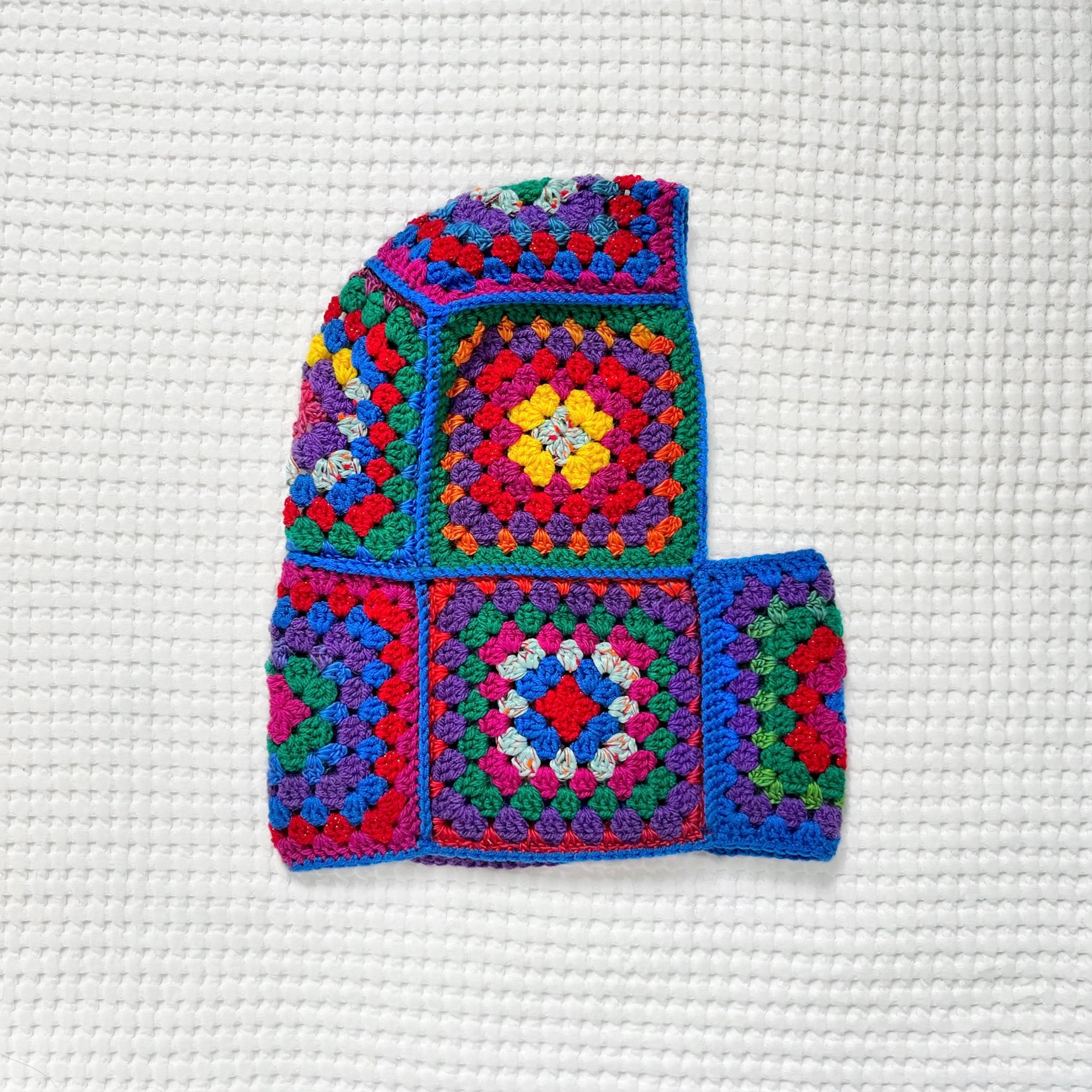 Colorful crocheted balaclava with geometric patterns on a white textured background