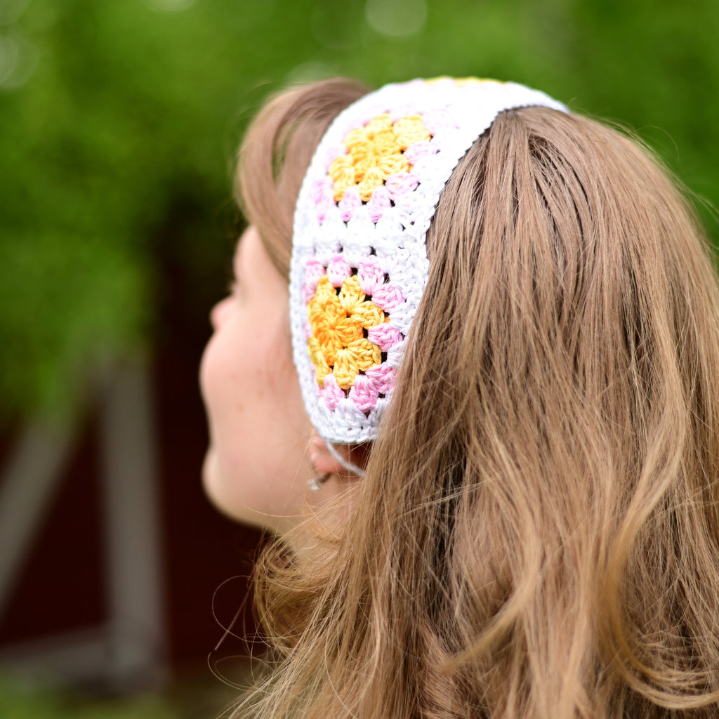 Person wearing a colorful crochet headband with a blurred green background