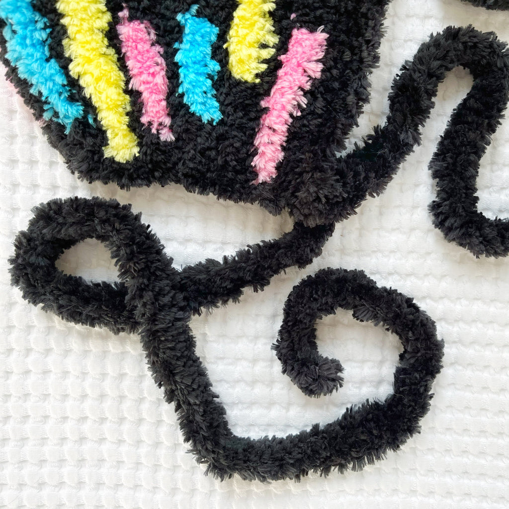 Decorative crochet bonnet with colorful yarn accents on a white background