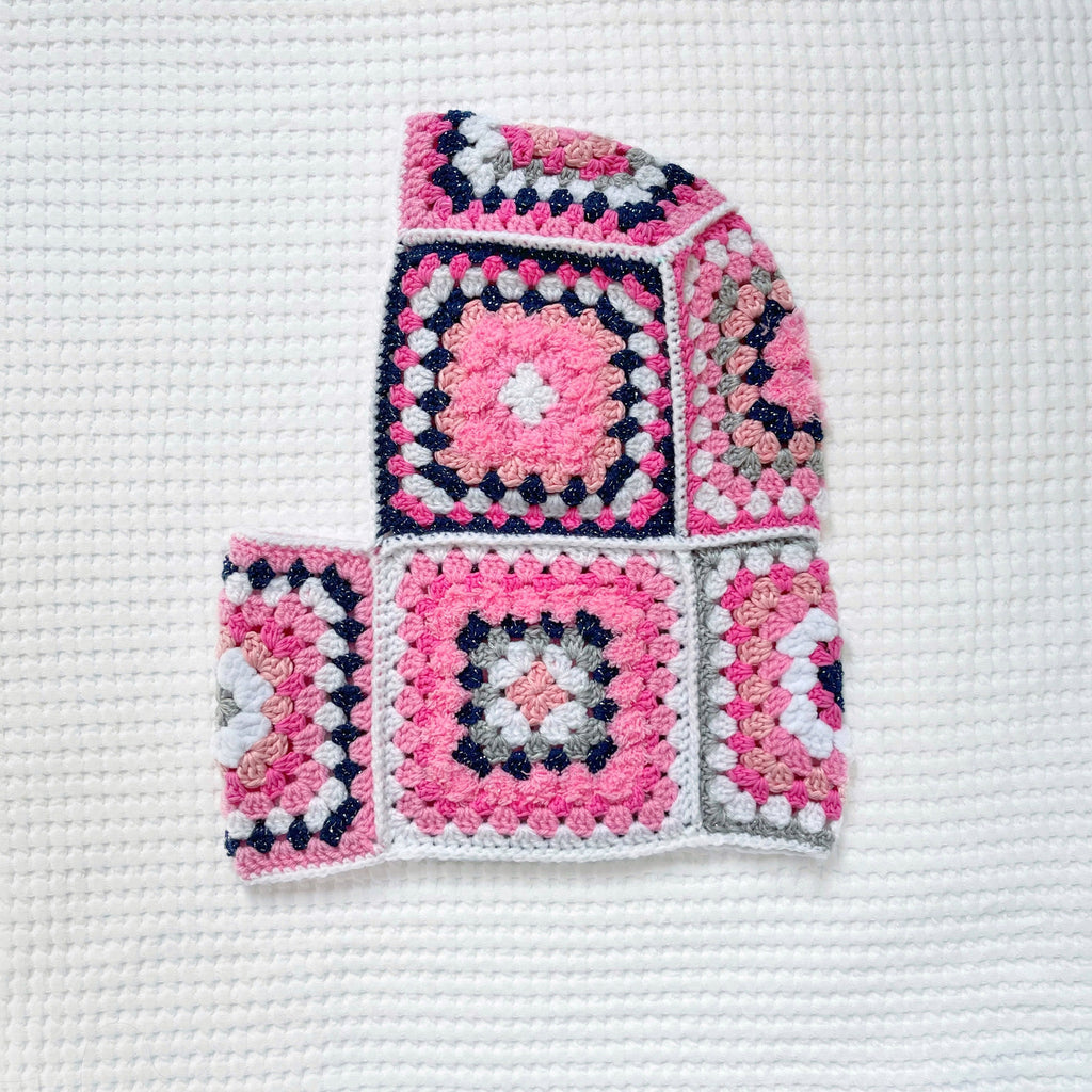 Crocheted balaclava with pink and blue pattern on a white background