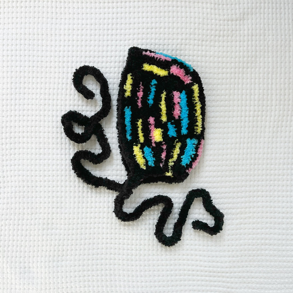 Crochet multicolored bonnet on a white fabric background