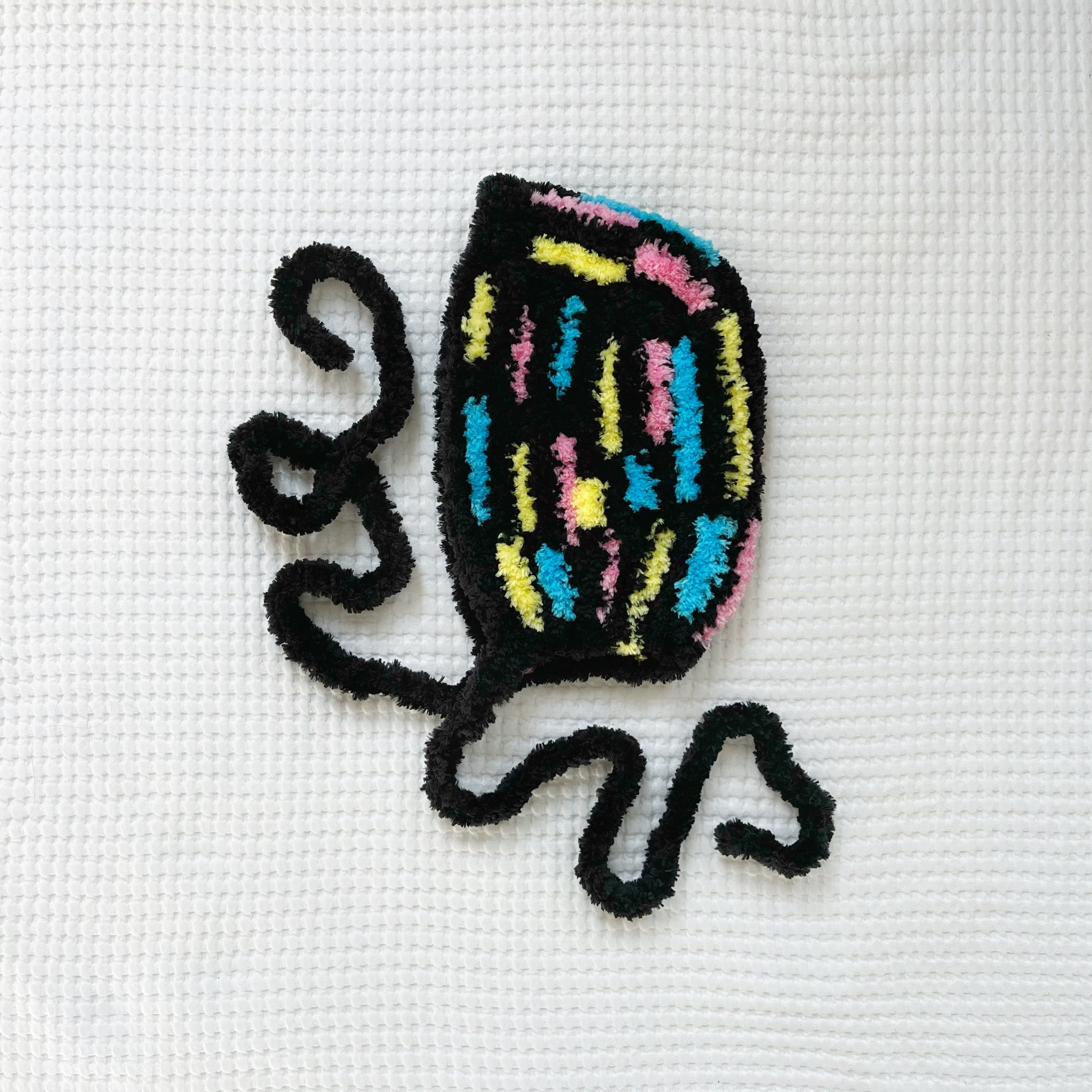 Crochet multicolored bonnet on a white fabric background