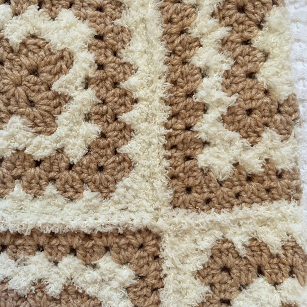 Crocheted balaclava in beige and white colors on a textured white background