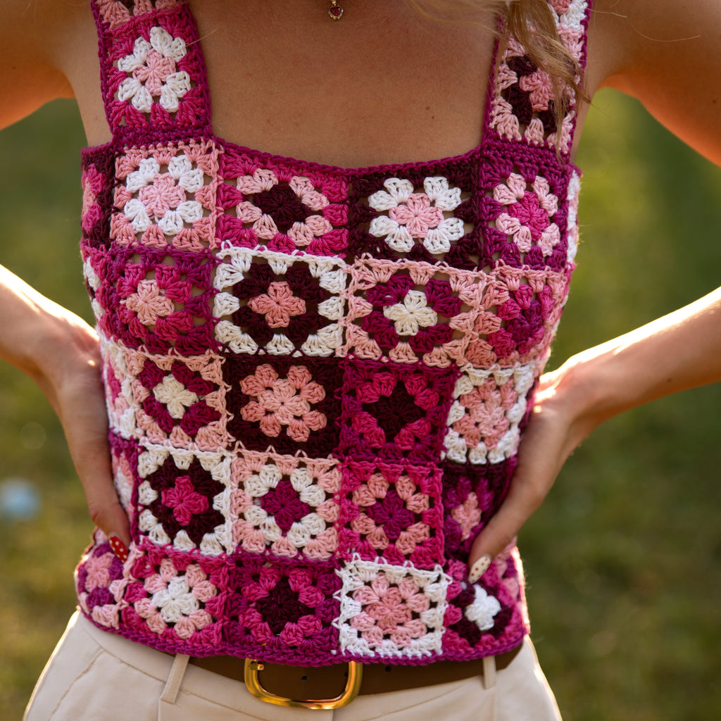 Person wearing a colorful crochet tank top with a blurred natural background