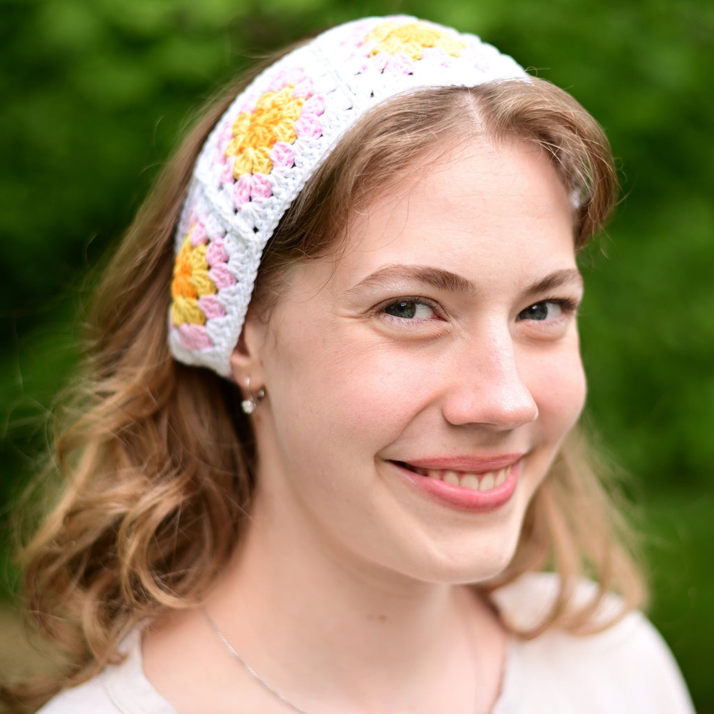Woman wearing a colorful crochet headband with a blurred green background