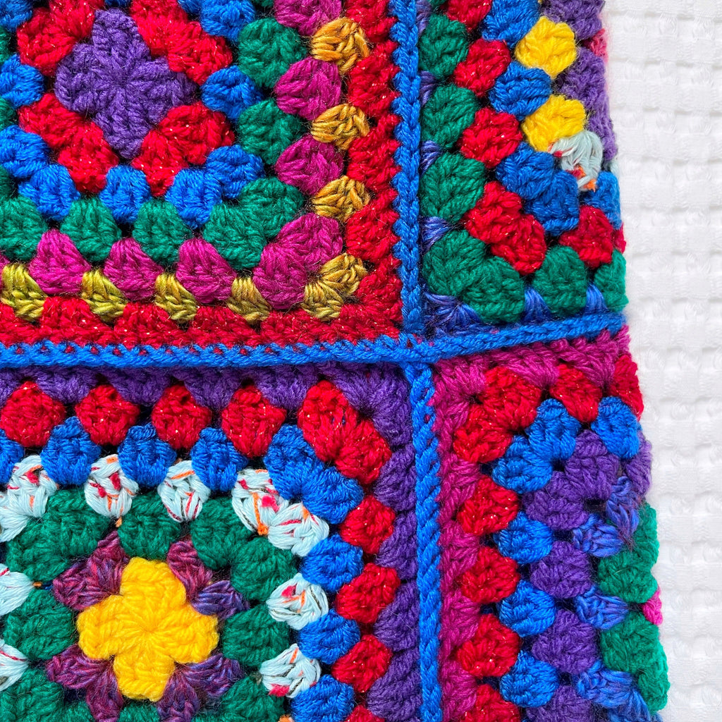 Colorful crocheted balaclava with granny square pattern on a white background