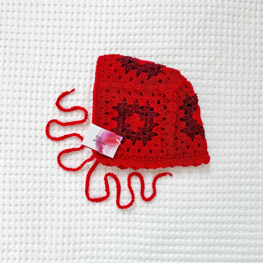 Red crochet glittery bonneton a white textured background