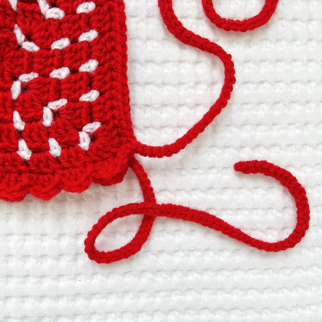 Red crochet bonnet with white accents on a white background