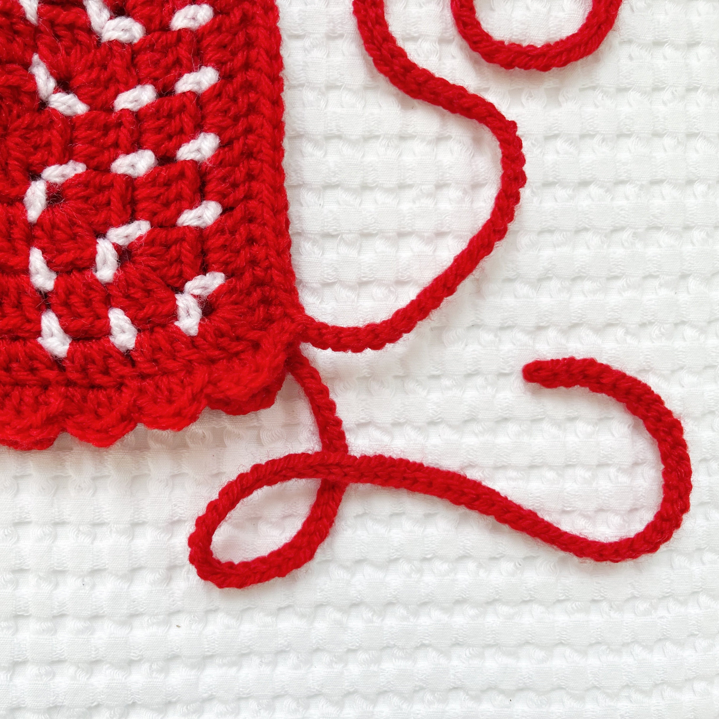 Red crochet bonnet with white accents on a white background