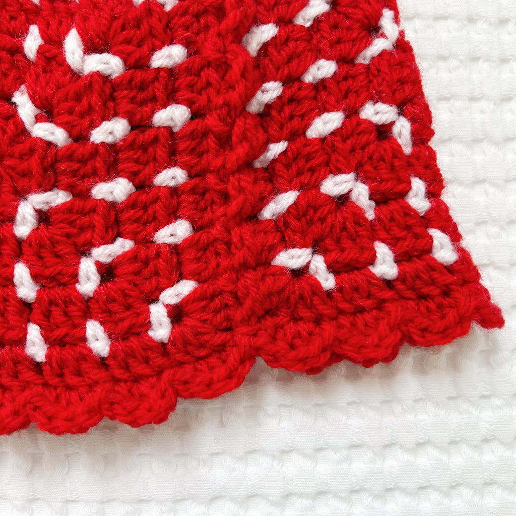 Red crocheted bonnet with white accents on a white background