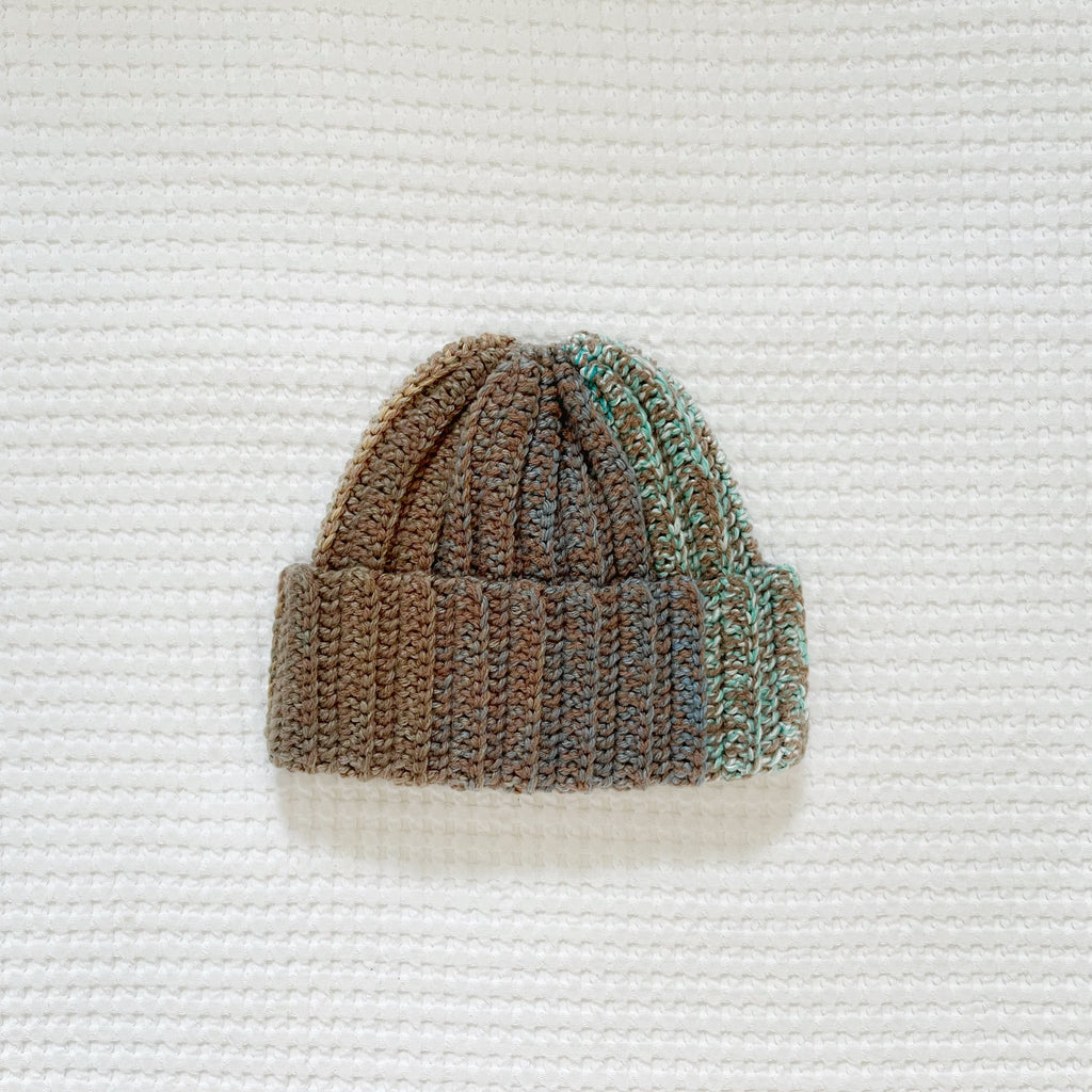 Crochet beanie hat on a textured white background