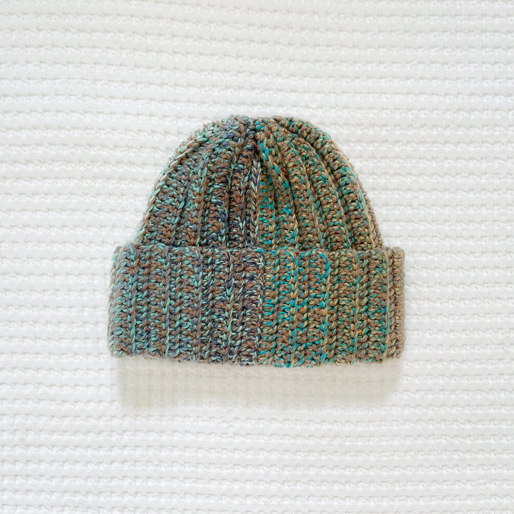 Crochet beanie with a gradient pattern on a textured white background