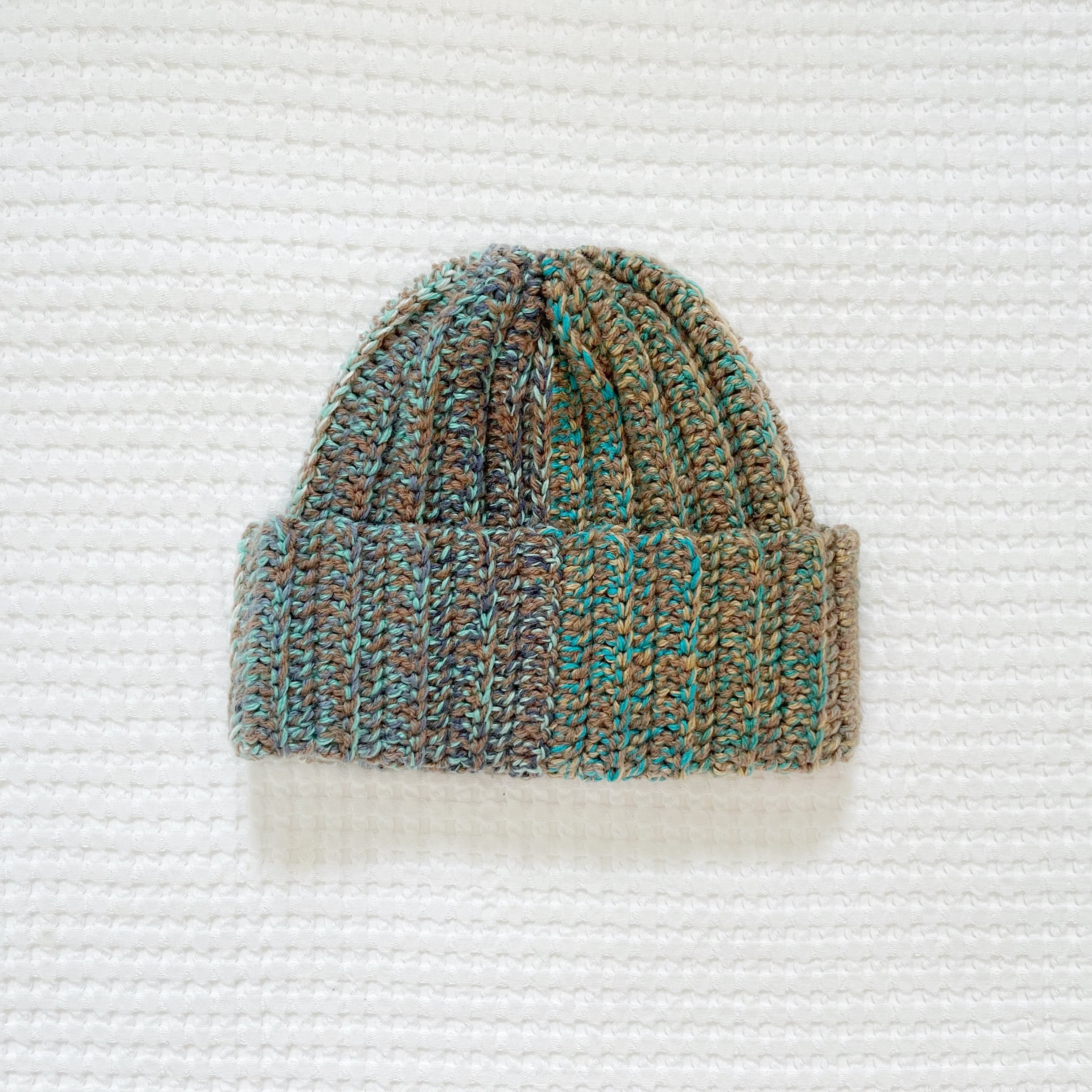 Crochet beanie with a gradient pattern on a textured white background