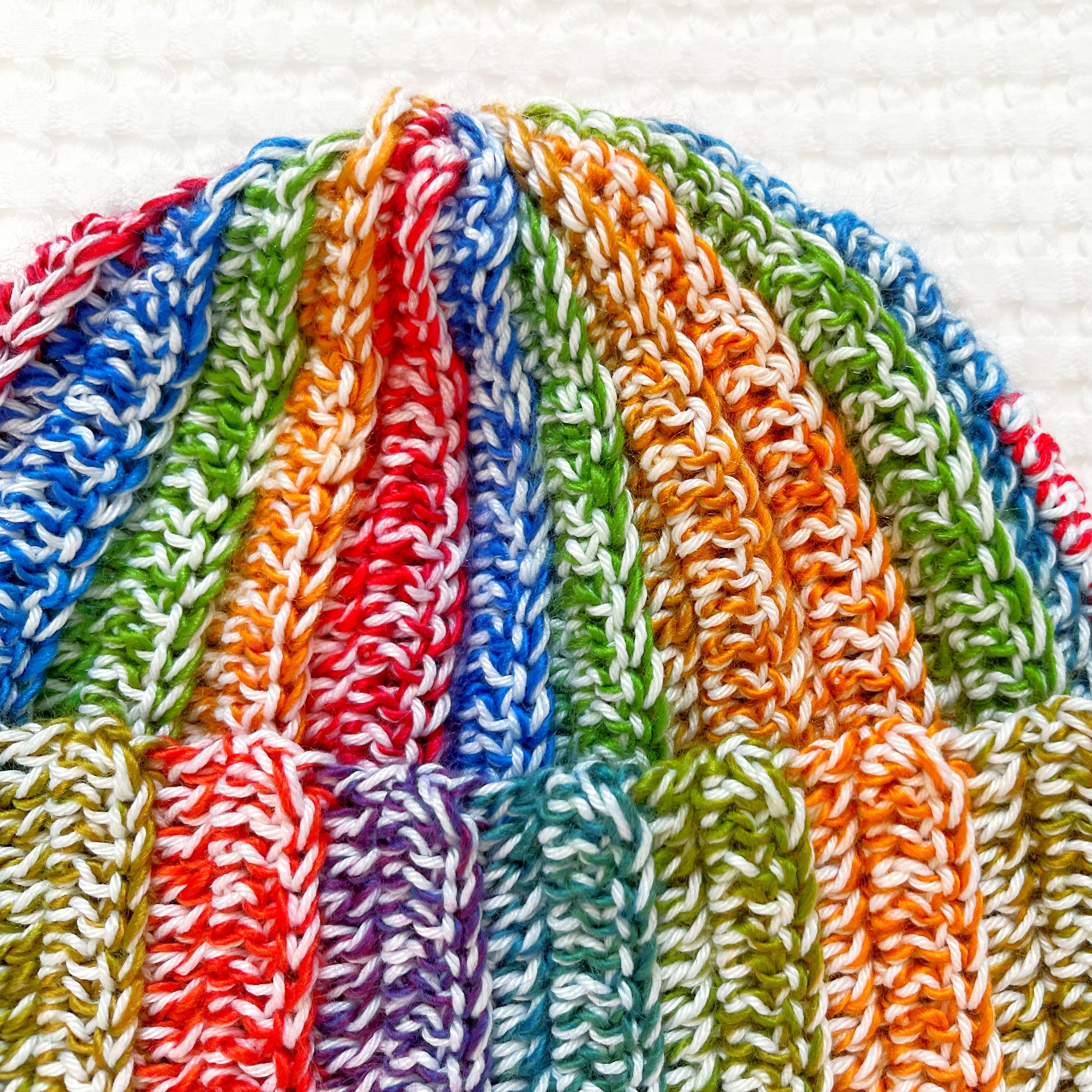 Close-up of a multicolored rainbow crochet beanie on a white background