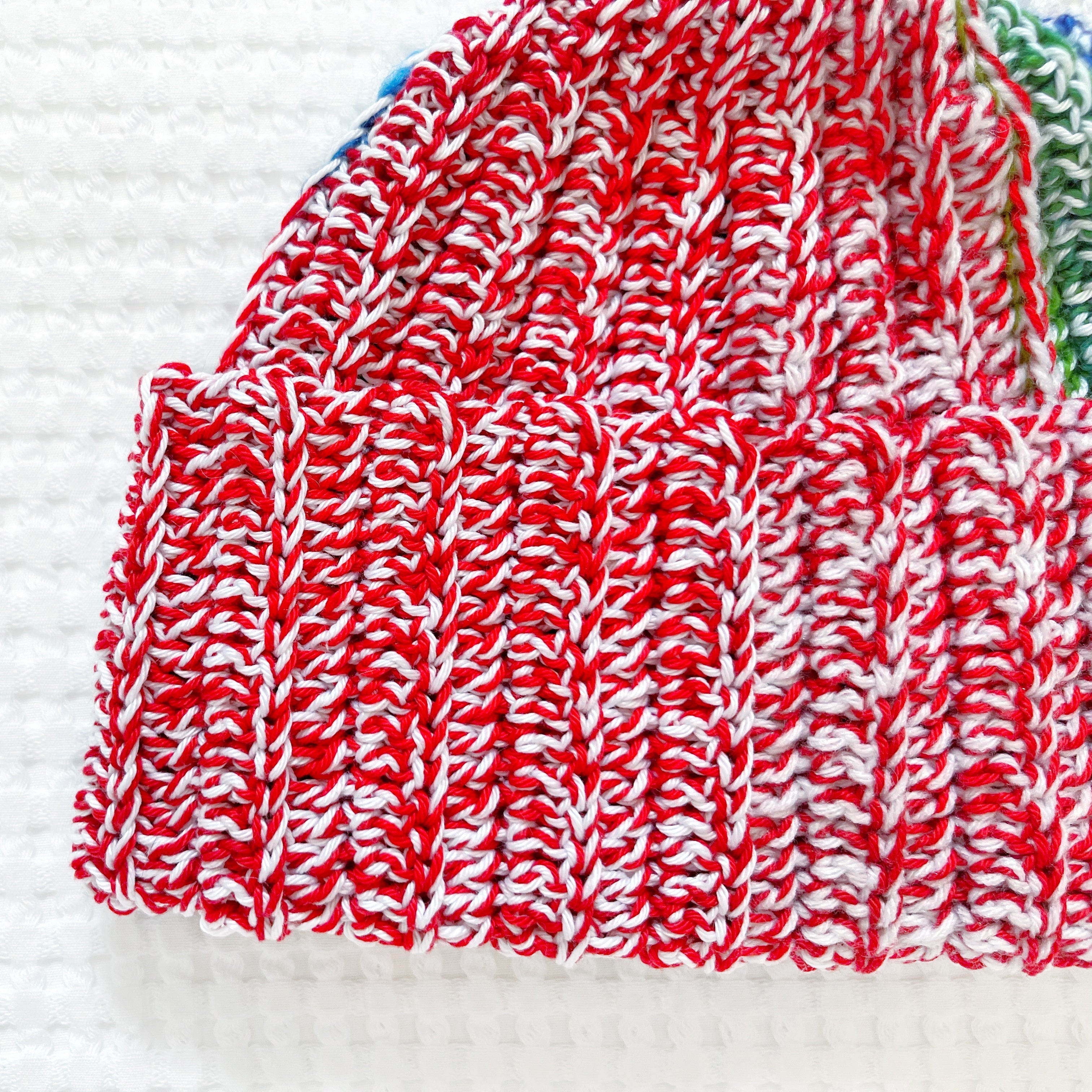 Close-up of a red and white rainbow crochet beanie on a white background