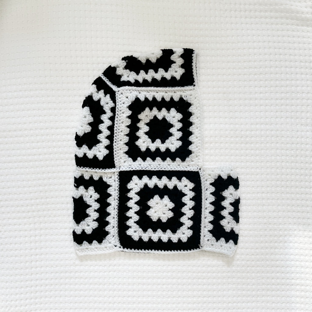 Black and white crocheted balaclava on a textured white background