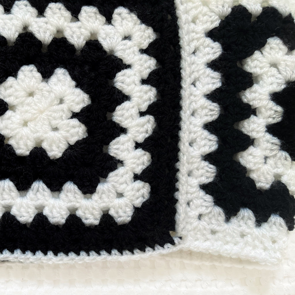 Black and white crocheted balaclava on a textured white background