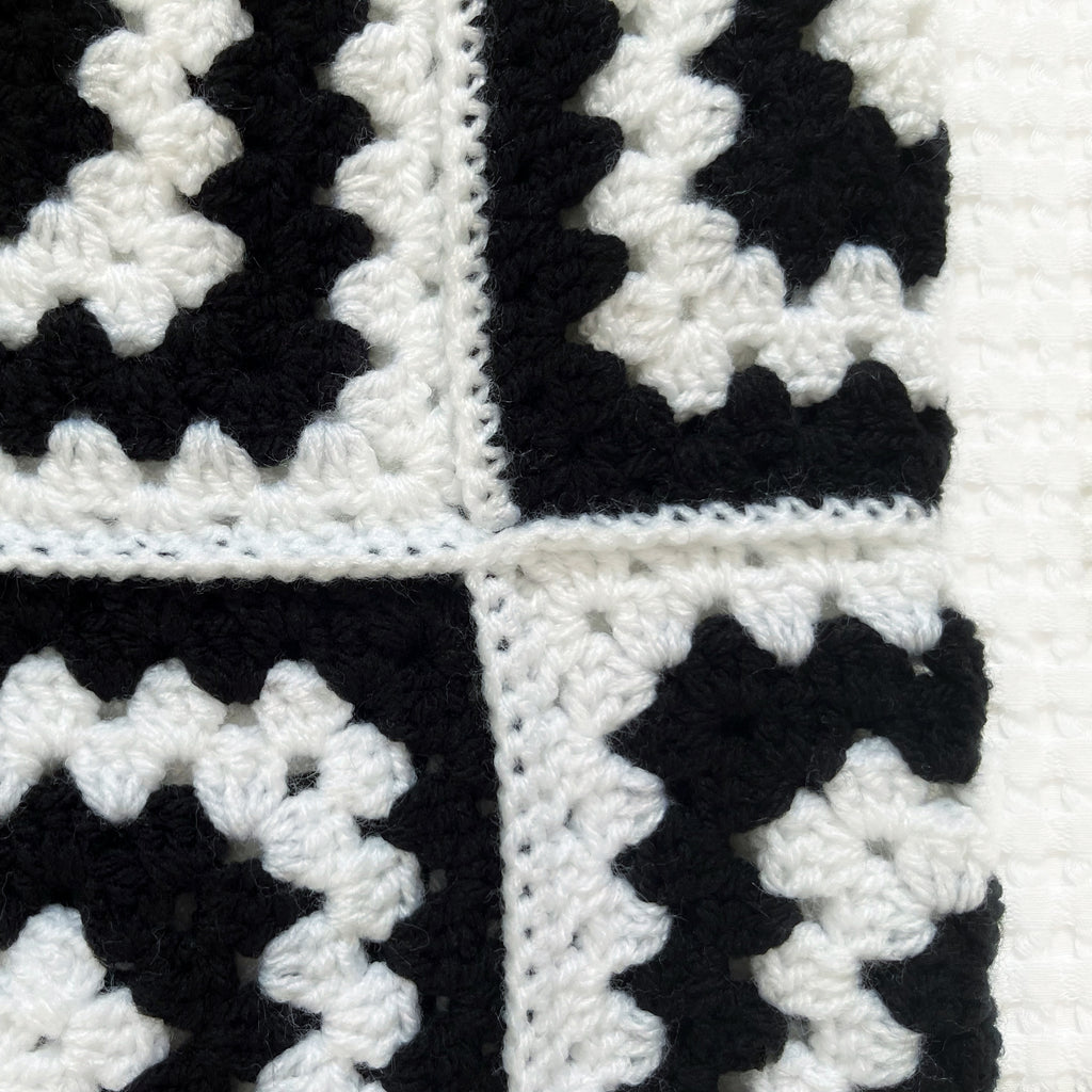 Black and white crocheted balaclava on a textured white background