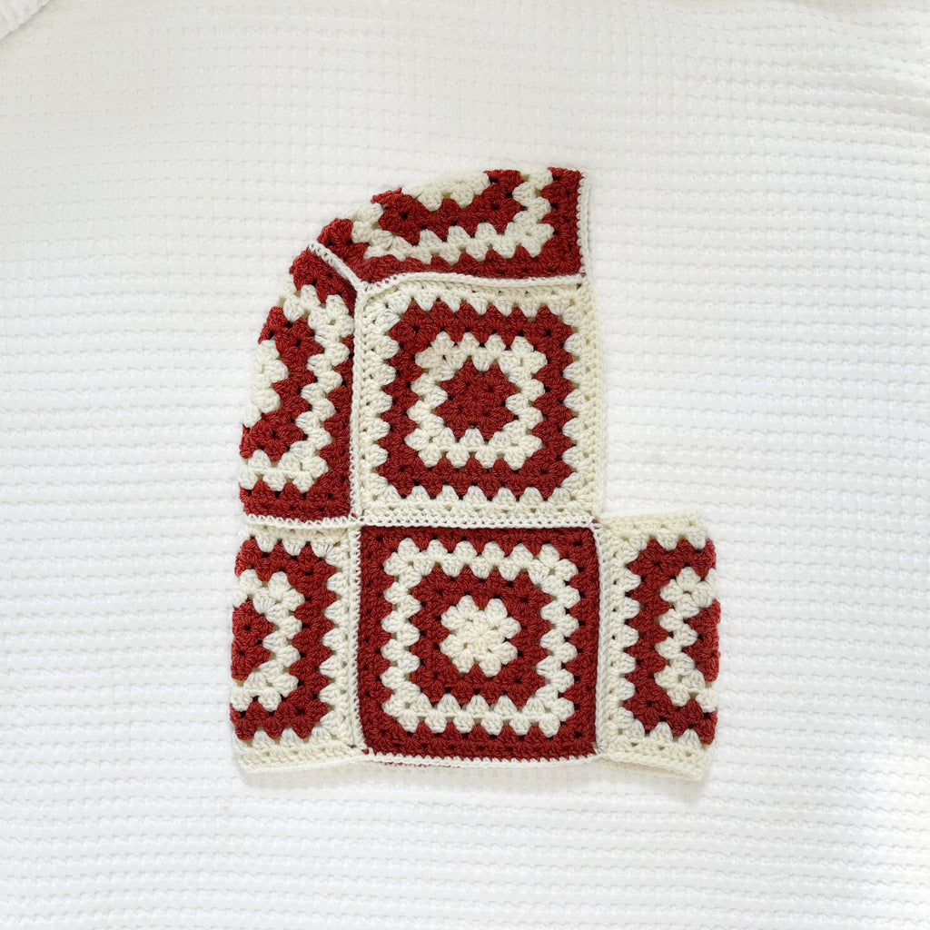 Crocheted balaclava with burgundy and white square pattern on a white background