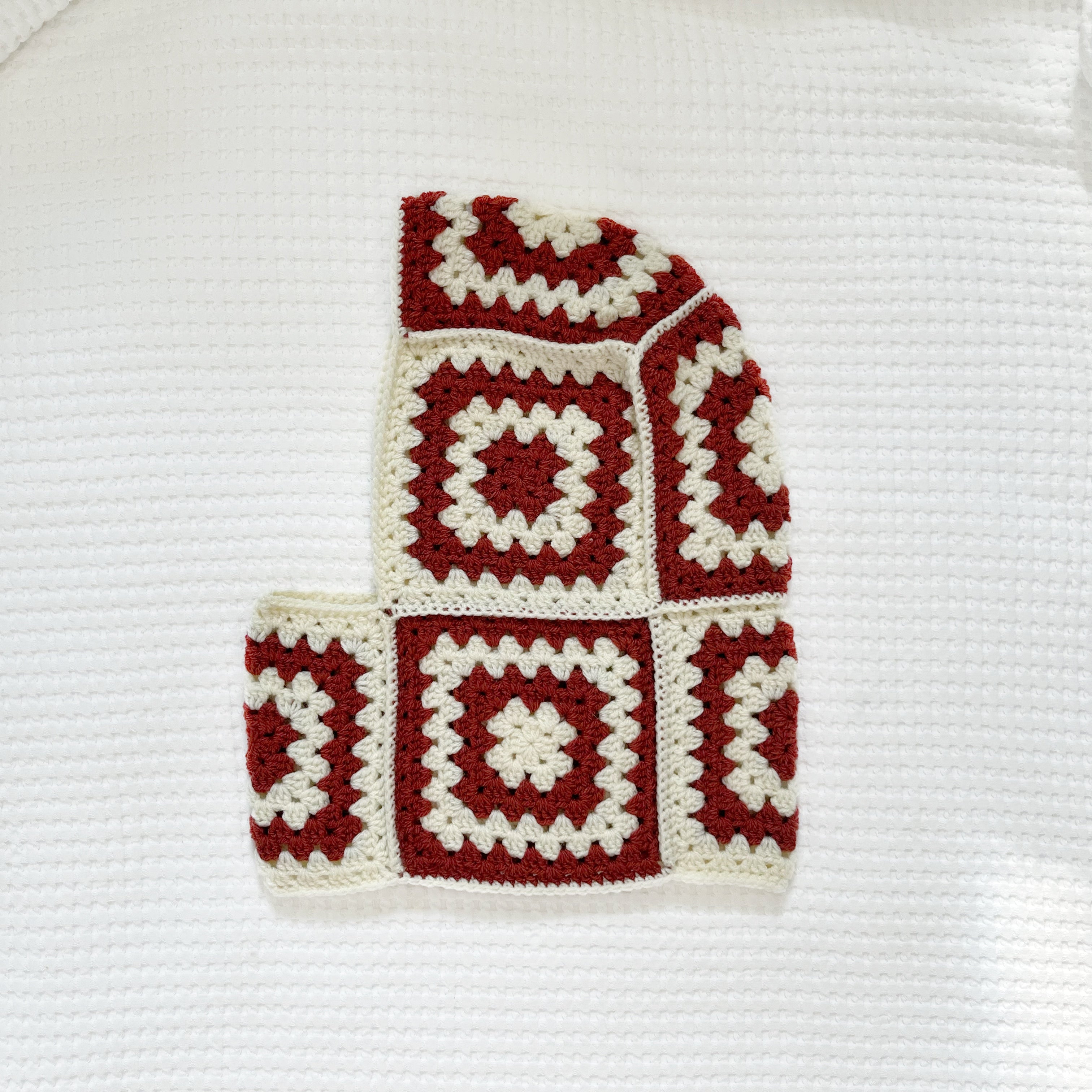 Crocheted balaclava with burgundy and white square pattern on a white background