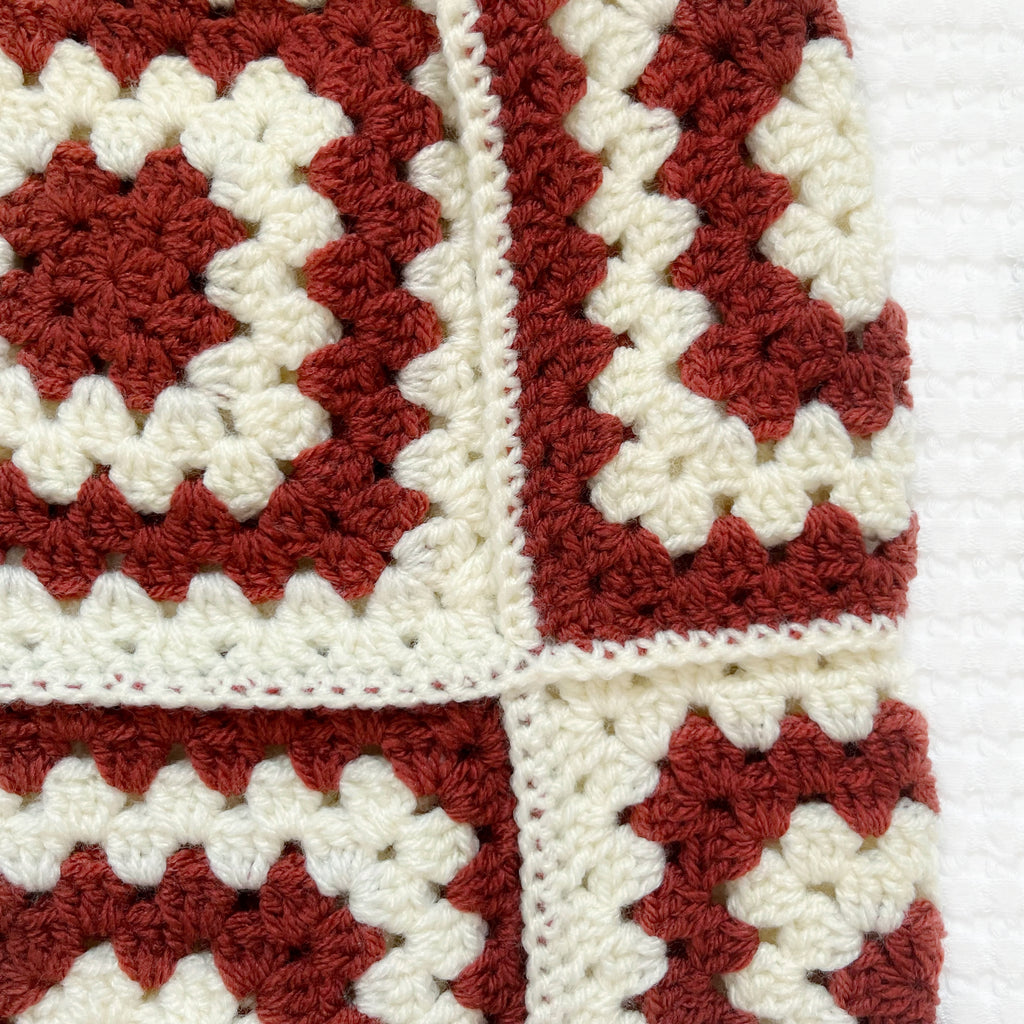 Crocheted balaclava with burgundy and white square pattern on a white background