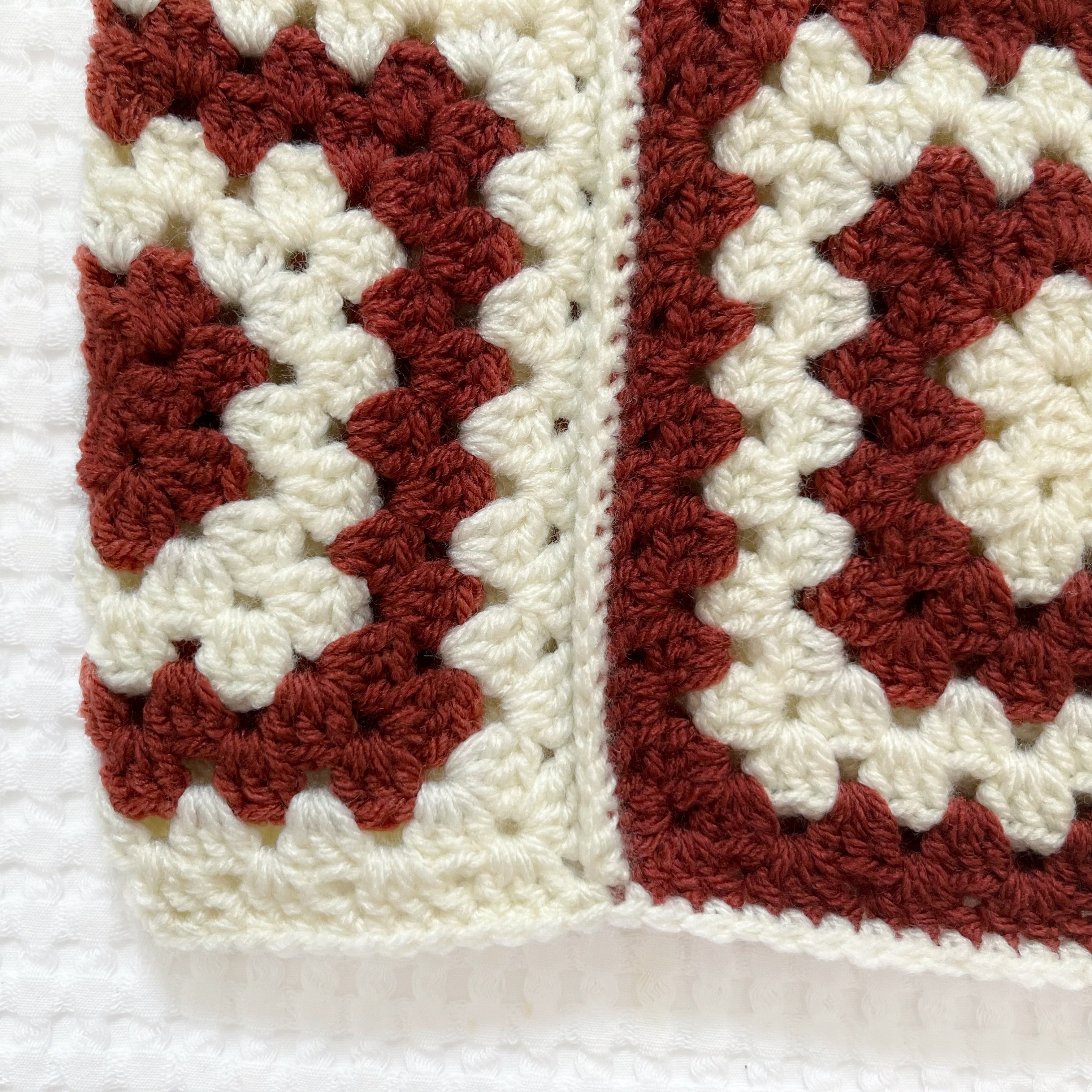 Crocheted balaclava with burgundy and white square pattern on a white background