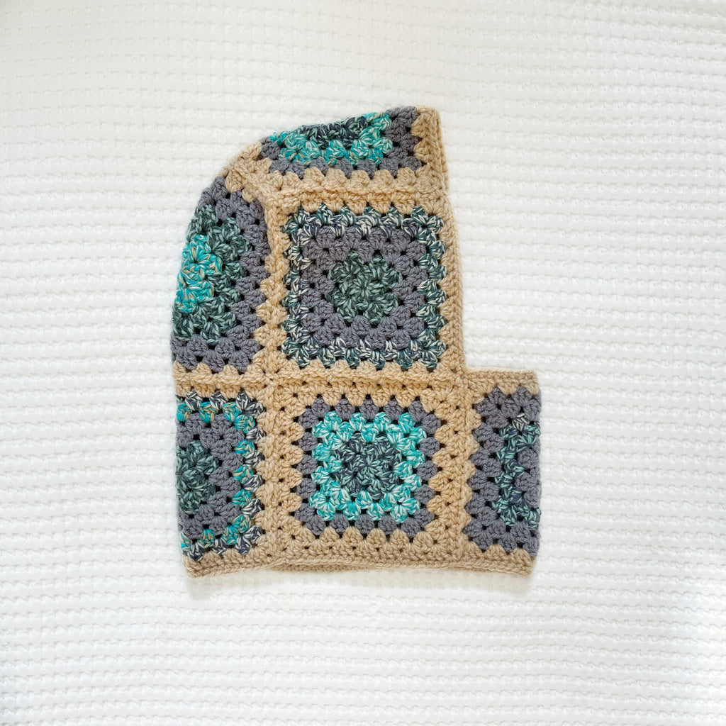 Crocheted balaclava with a square pattern on a textured white background