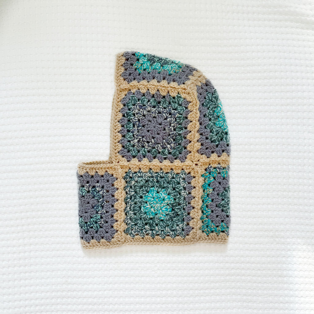 Crocheted balaclava with a square pattern on a textured white background