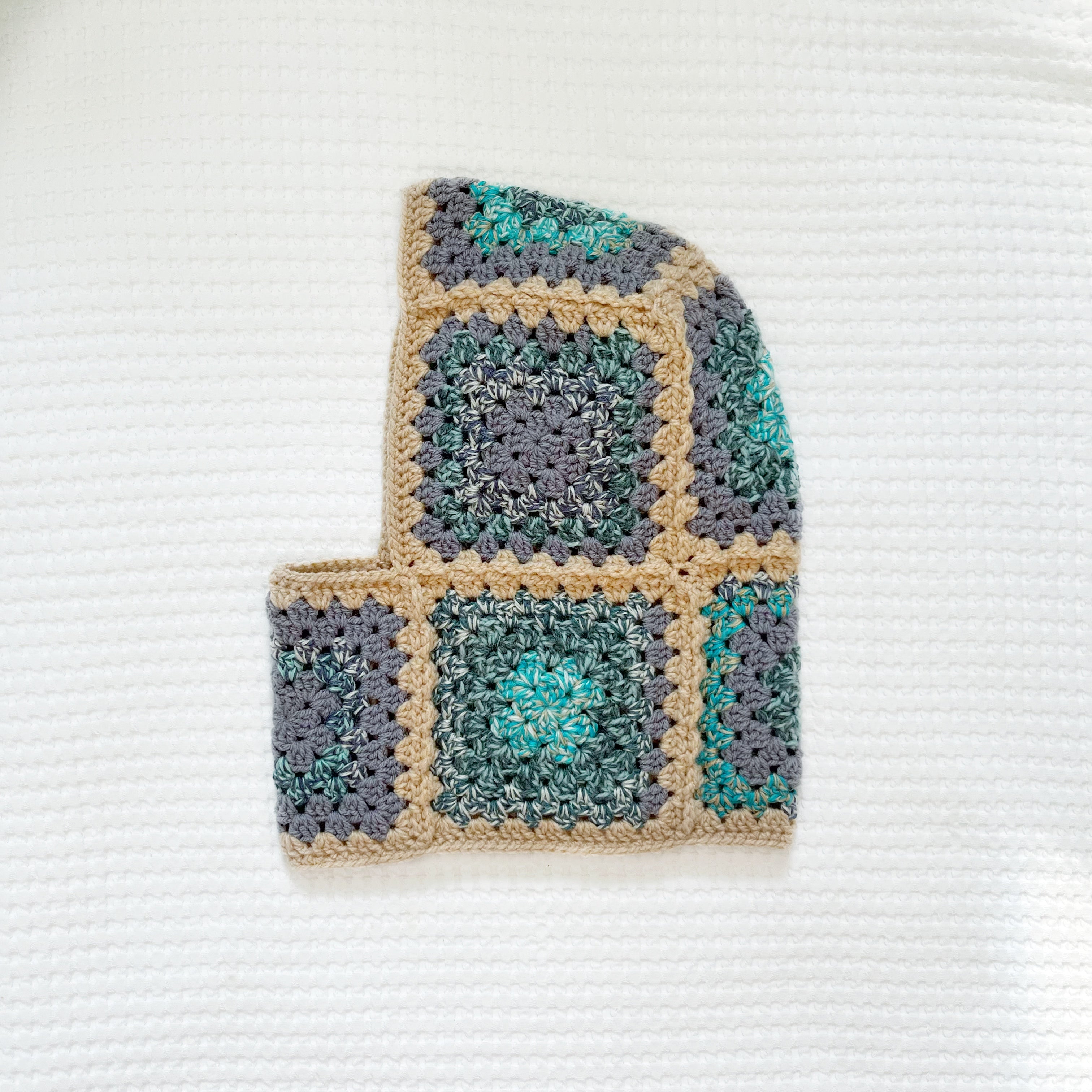 Crocheted balaclava with a square pattern on a textured white background