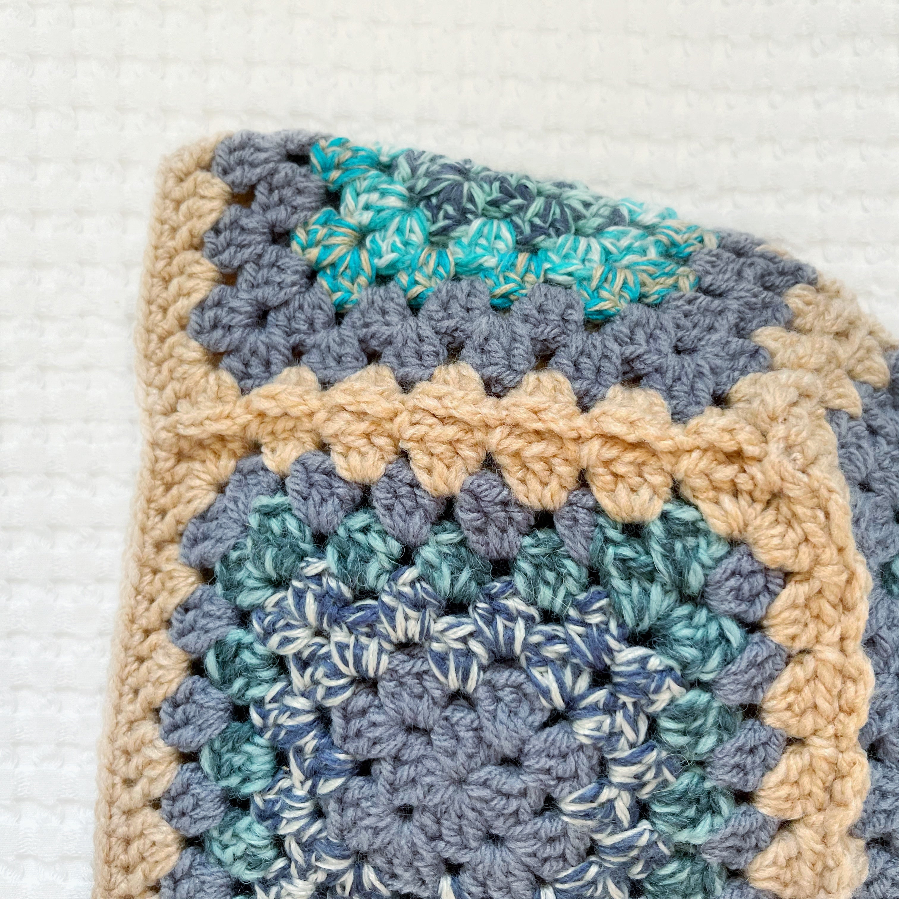 Crocheted balaclava with a square pattern on a textured white background