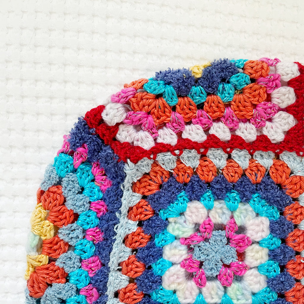 Colorful crocheted balaclava with square patterns on a white background