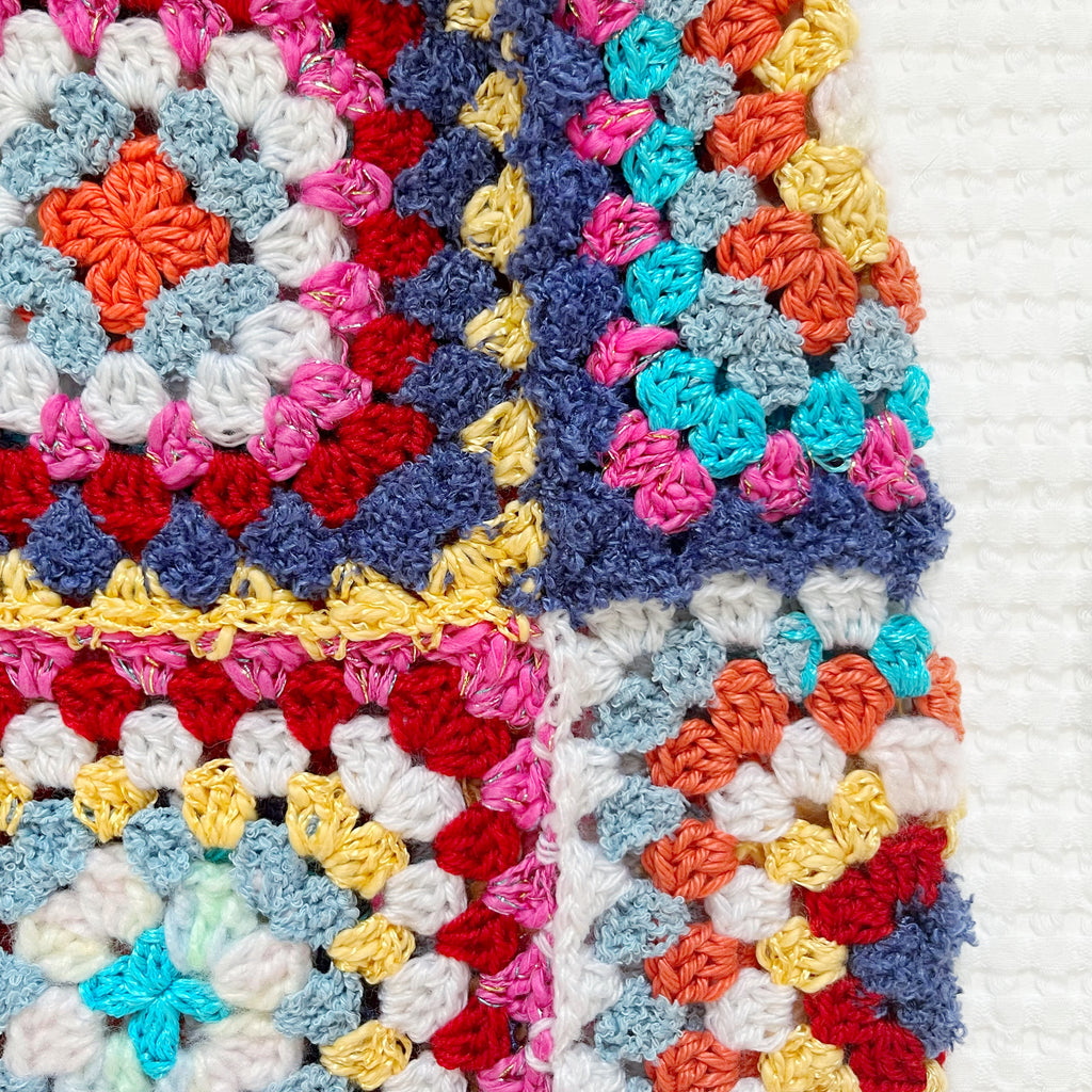 Colorful crocheted balaclava with square patterns on a white background